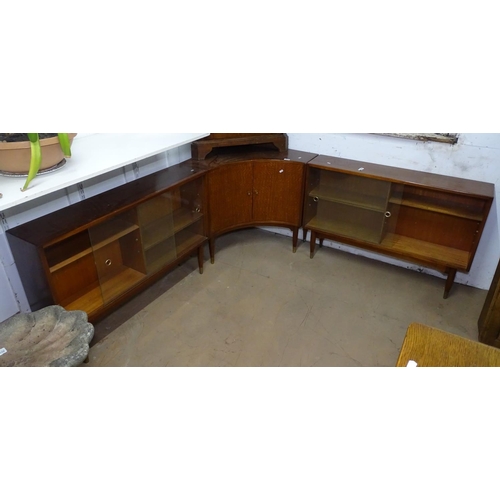 1329 - A mid-century teak 3-section corner bookcase, with sliding glazed and cupboard doors, on turned legs... 