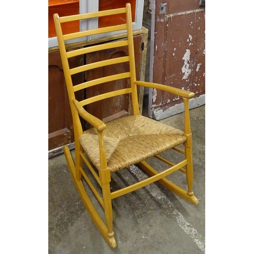 1565 - A beech ladder-back rush-seated rocking chair, a painted 2-door hanging cabinet, and a pine 2-door c... 