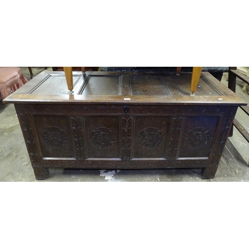 1599 - An 18th century oak coffer, with panelled top and chip carved panelled front, on stile legs, L148cm