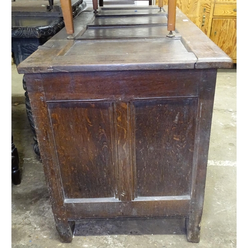 1599 - An 18th century oak coffer, with panelled top and chip carved panelled front, on stile legs, L148cm