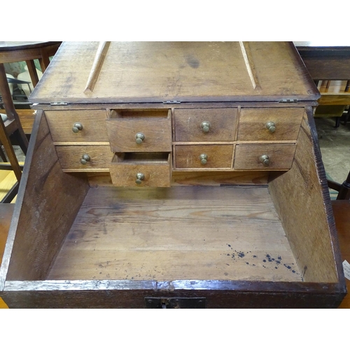 1631 - An 18th century oak clerk's writing slope, the rising lid revealing fitted drawers, with brass lock ... 