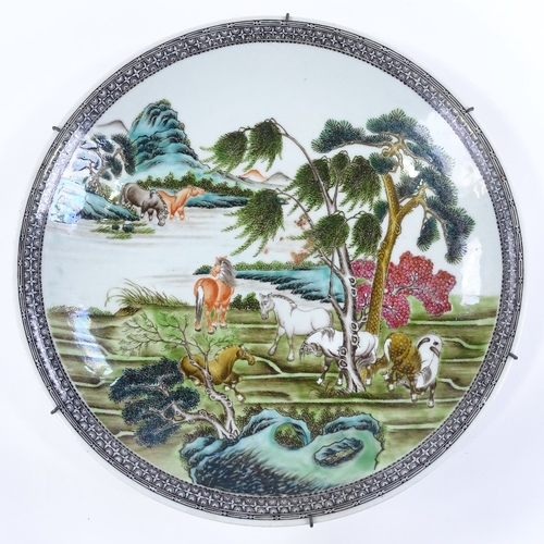 22 - A Chinese porcelain charger, hand painted enamel horses in landscape with painted geometric border, ... 