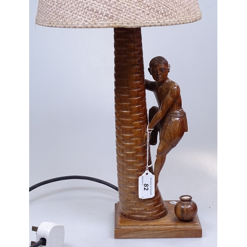 82 - An Indian carved wood table lamp, in the form of a boy climbing a palm tree, height excluding fittin... 