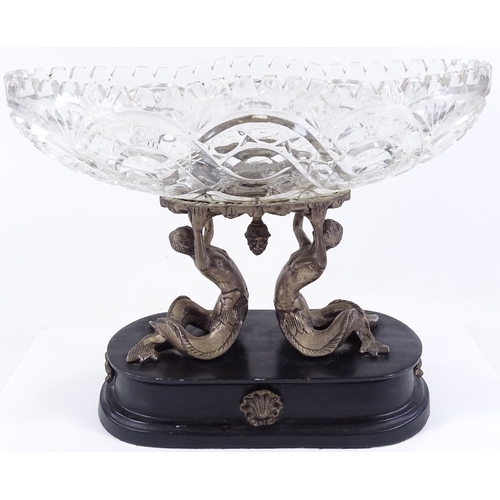 112 - A cut-glass table centre bowl supported by electroplate mermaid figures, on ebonised plinth, length ... 