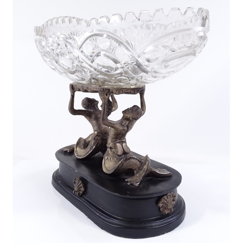 112 - A cut-glass table centre bowl supported by electroplate mermaid figures, on ebonised plinth, length ... 