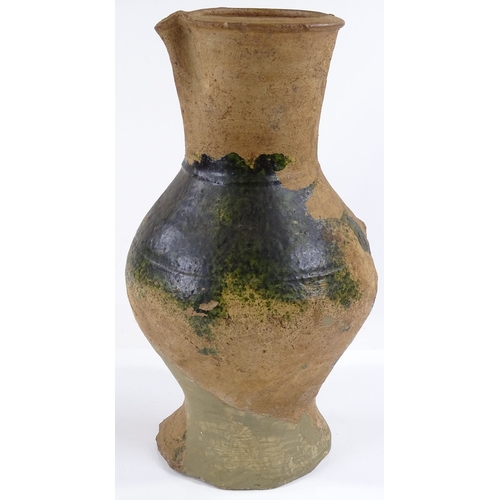 131 - A Medieval terracotta jug with parts of original green glaze A/F, height 31cm