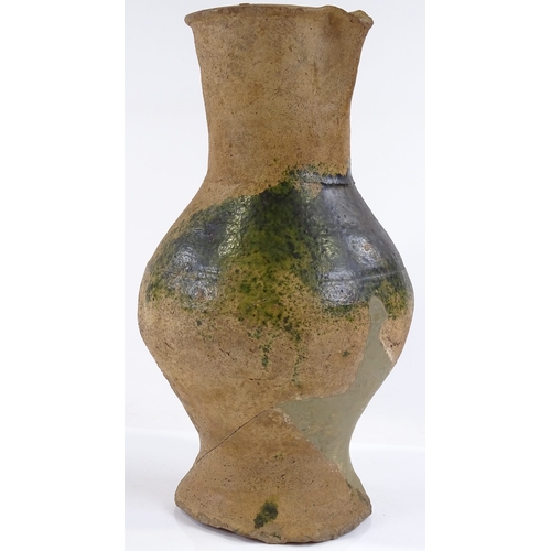 131 - A Medieval terracotta jug with parts of original green glaze A/F, height 31cm