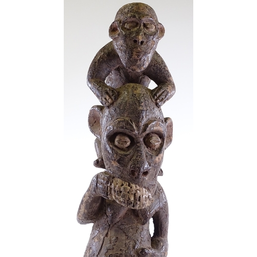 61 - An African carved and painted wood sculpture of a monkey riding on a man's shoulders, height 80cm