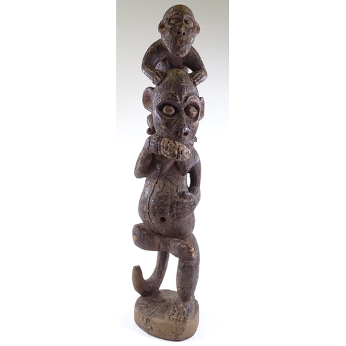 61 - An African carved and painted wood sculpture of a monkey riding on a man's shoulders, height 80cm