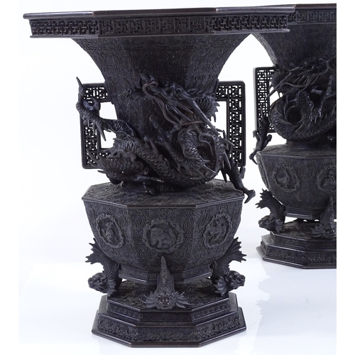 119 - A pair of Japanese Meiji period bronze vases, 3-dimensional dragon mounted necks, with pierced friez... 