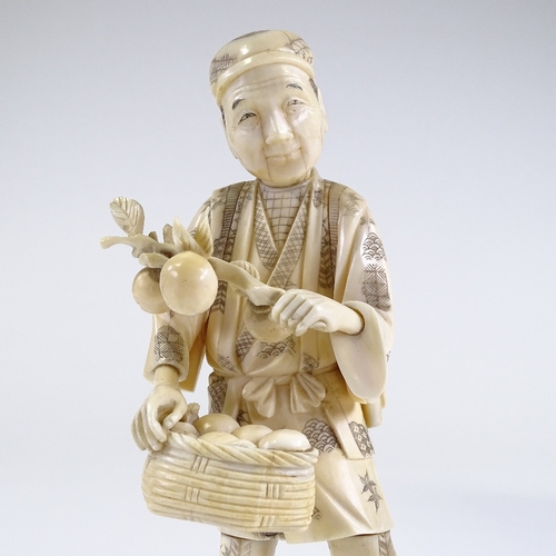 11 - A Japanese Meiji period sectional carved ivory figure of a farmer carrying fruit, carved hardwood st... 