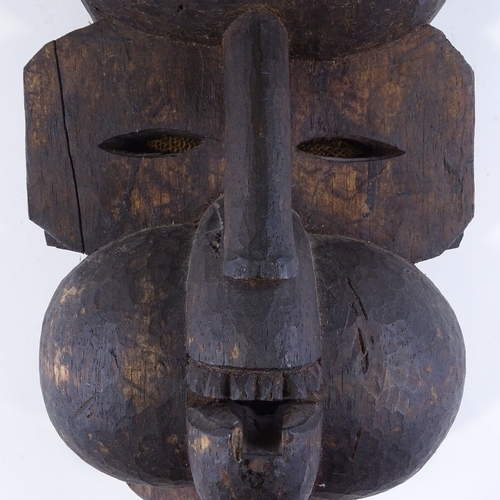 112 - An African Ibibio carved and stained wood Tribal mask, in the form of a cooking pot above a baboon's... 