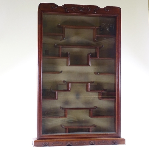 117 - A Chinese hardwood snuff bottle display cabinet, with relief carved surround and stepped shelved int... 