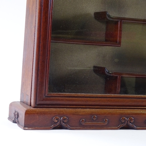 117 - A Chinese hardwood snuff bottle display cabinet, with relief carved surround and stepped shelved int... 