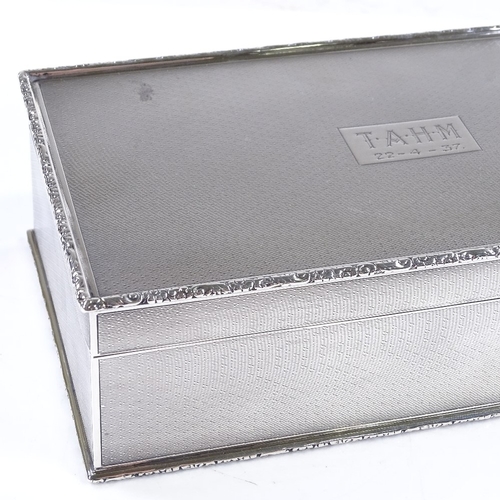 587 - A George V rectangular silver cigarette box, all over engine turned decoration with relief embossed ... 