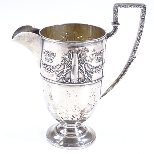 590 - An Edwardian silver helmet-shaped cream jug, with relief embossed Adams style decoration, and gilt i... 