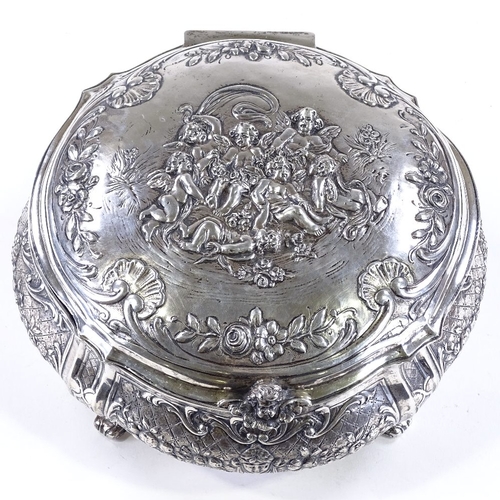 613 - A large German circular silver box, with hinged lid, on scrolled acanthus leaf feet, relief embossed... 