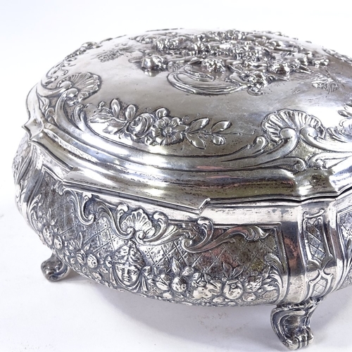 613 - A large German circular silver box, with hinged lid, on scrolled acanthus leaf feet, relief embossed... 