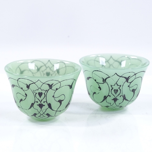 177 - A pair of Islamic green glass tea bowls with painted decoration, diameter 6cm