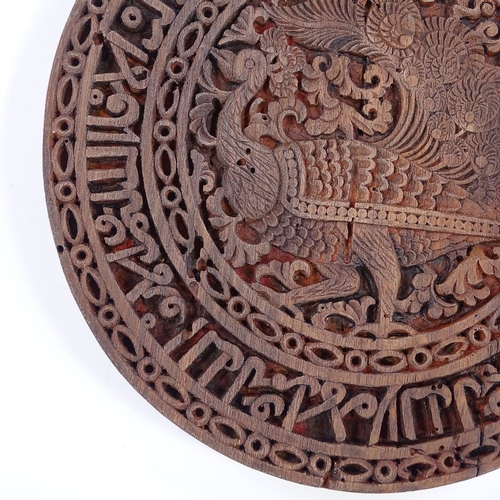 178 - An Islamic wooden stand with relief carved peacock and text design, diameter 19cm