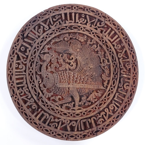 178 - An Islamic wooden stand with relief carved peacock and text design, diameter 19cm