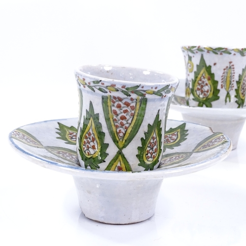 181 - A pair of Turkish pottery coffee cups and saucers, with painted decoration