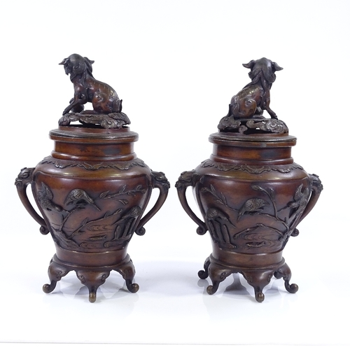 199 - A pair of Oriental patinated bronze vases and covers, with Dog of Fo knops and bird decorated relief... 