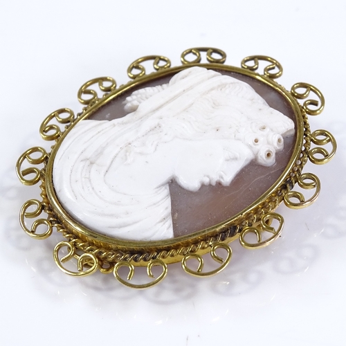 448 - An oval relief carved cameo shell panel brooch, depicting Classical female portrait, in 9ct gold rop... 