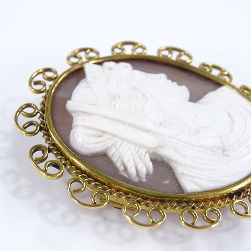 448 - An oval relief carved cameo shell panel brooch, depicting Classical female portrait, in 9ct gold rop... 