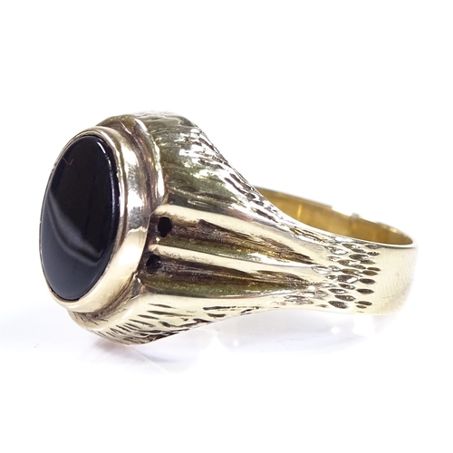 450 - A large unmarked gold onyx signet ring, with brushed bridge and shoulders, setting height 17mm, size... 