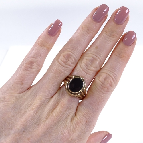 450 - A large unmarked gold onyx signet ring, with brushed bridge and shoulders, setting height 17mm, size... 