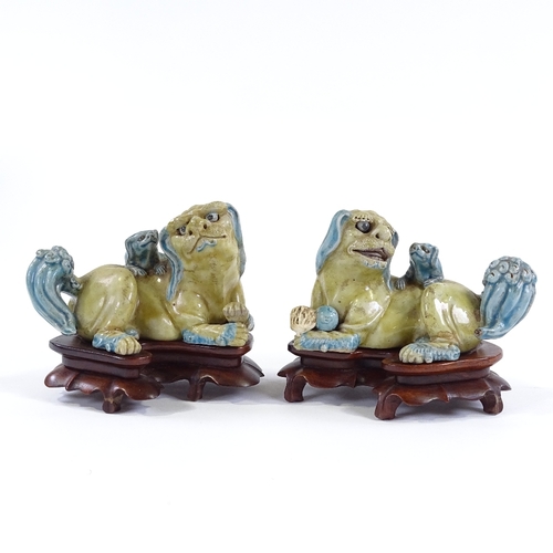 11 - A pair of Chinese glazed porcelain Dogs of Fo, on original carved rosewood stands, length 14cm