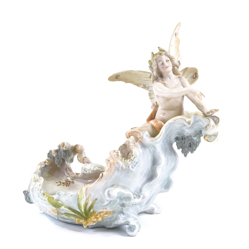 134 - A German porcelain table centre bowl, surmounted by a winged nymph, blue glaze cross forks marks, le... 