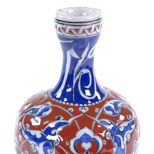 84 - A Turkish red and blue glaze narrow-necked bottle with painted enamel decoration, height 19cm