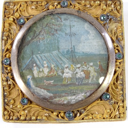 212 - A 19th century Indian miniature watercolour depicting an encampment, in ornate jewel set gilt-metal ... 