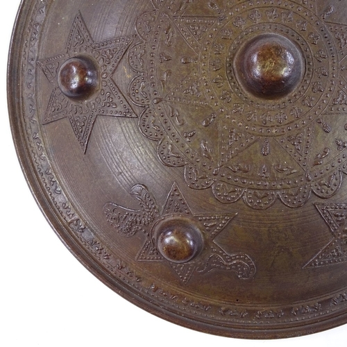 255 - A Middle Eastern bronze shield with relief decoration, 27cm across