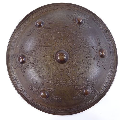 255 - A Middle Eastern bronze shield with relief decoration, 27cm across