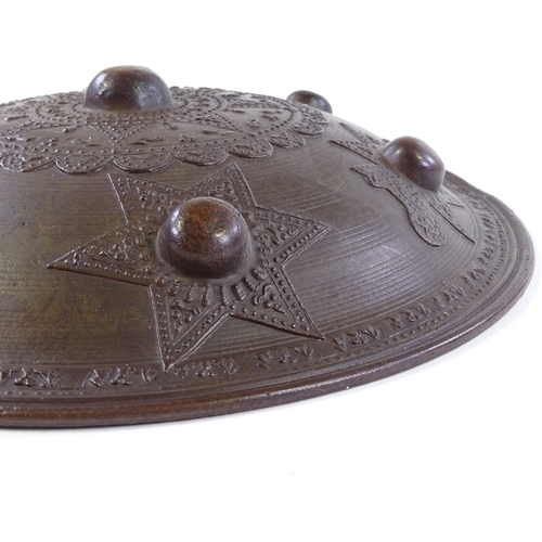 255 - A Middle Eastern bronze shield with relief decoration, 27cm across