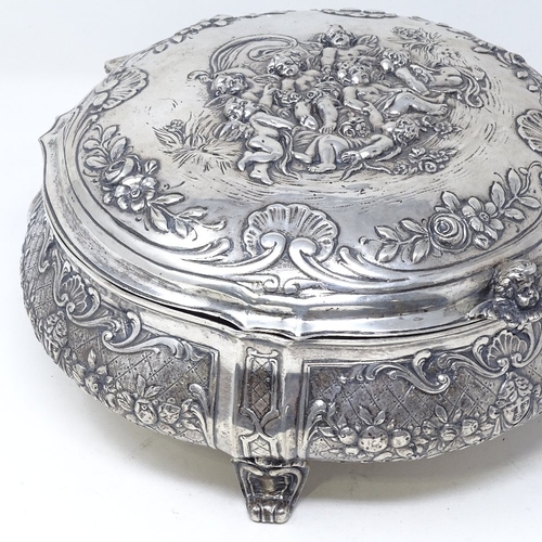 845 - A large German circular silver box, with hinged lid, on scrolled acanthus leaf feet, relief embossed... 