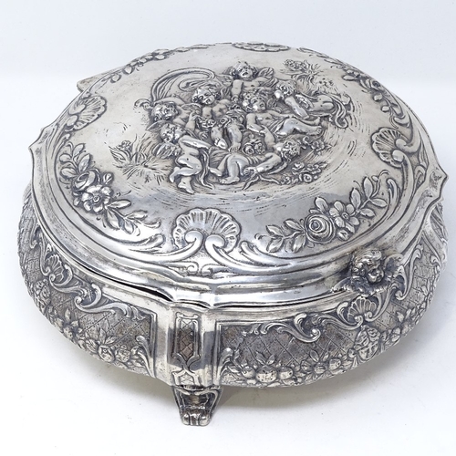 845 - A large German circular silver box, with hinged lid, on scrolled acanthus leaf feet, relief embossed... 