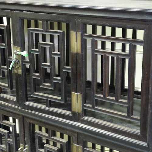 337 - A Chinese 19th century hardwood cupboard with fretwork panels and doors, width 3'11