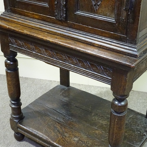 339 - An Antique carved and panelled oak 2-door cupboard on stand, 33.5