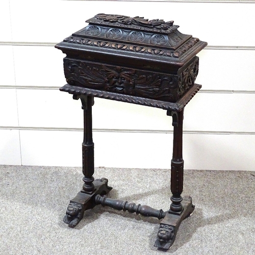 346 - A Victorian carved oak sewing box on stand with high relief carved decoration, on lion mask feet, wi... 