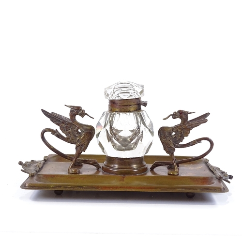 129 - A Victorian brass desk stand, with original cut-glass inkwell flanked by griffon figures