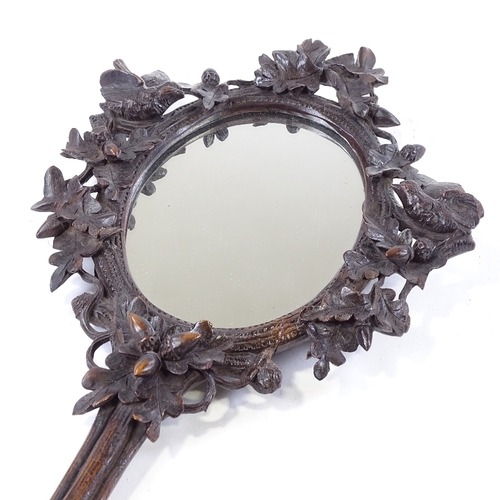 163 - A 19th century Black Forest carved wood framed hand mirror, surrounded by birds and acorns, length 3... 