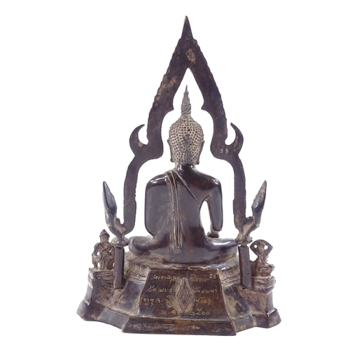 104 - An Oriental patinated bronze seated Buddha with shaped canopy above, text inscription to reverse, he... 