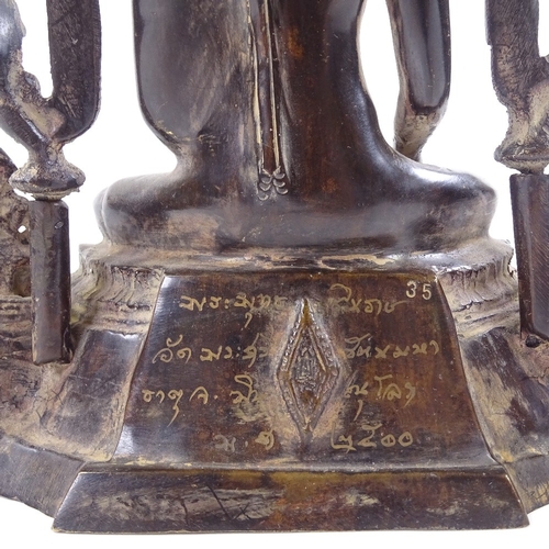 104 - An Oriental patinated bronze seated Buddha with shaped canopy above, text inscription to reverse, he... 