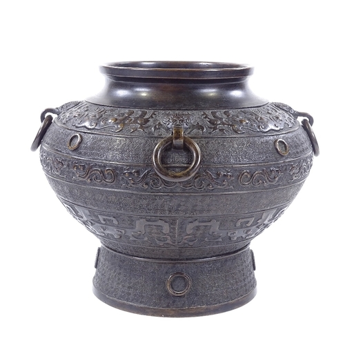 94 - A Chinese patinated bronze jardiniere with neck ring handles and relief moulded bands, impressed mar... 