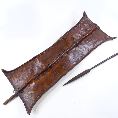 186 - An African leather-fronted Tribal shield, panel height 89cm, and a steel-tipped spear