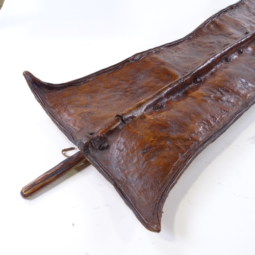 186 - An African leather-fronted Tribal shield, panel height 89cm, and a steel-tipped spear